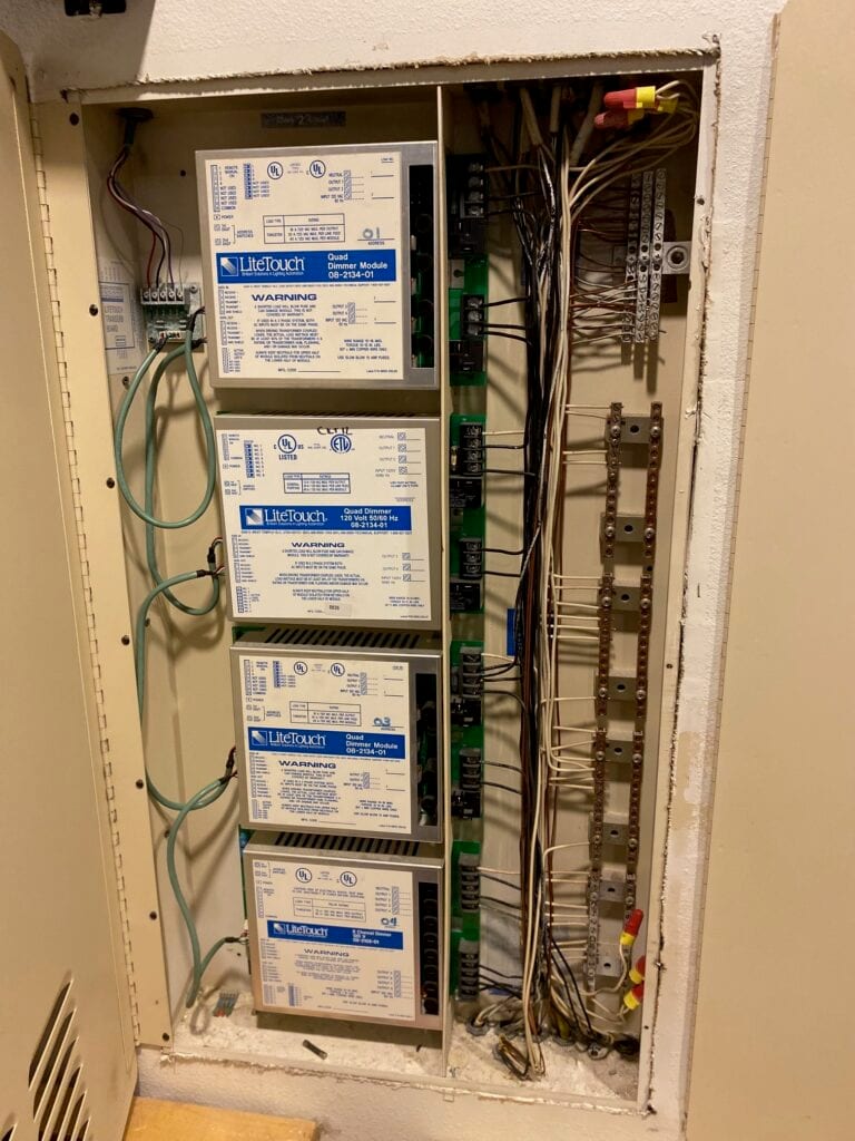 A LiteTouch lighting control enclosure open in a wall, showing quad dimmer modules and the original wiring